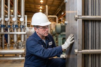 Ingénieur industriel inspectant un échangeur thermique à plaques en acier inoxydable dans une usine moderne