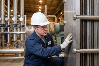 Ingénieur industriel inspectant un échangeur thermique à plaques en acier inoxydable dans une usine moderne
